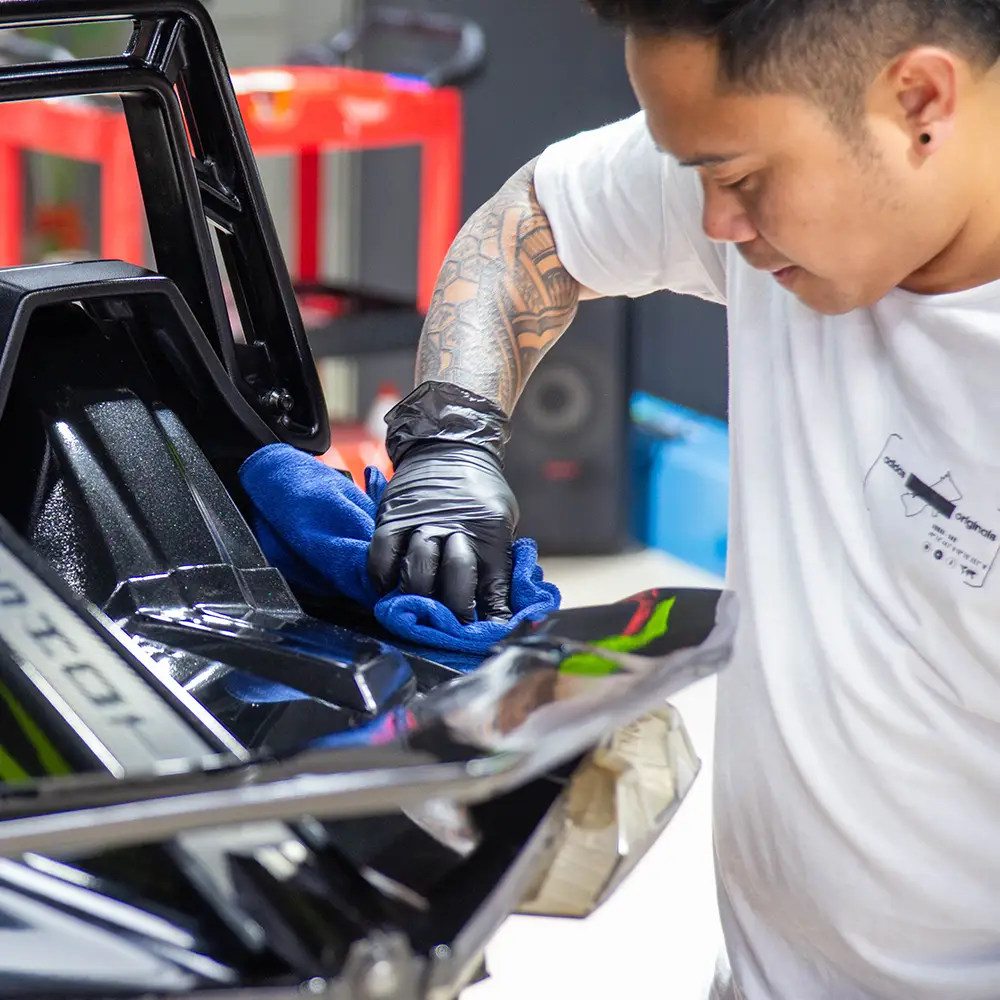 Detailer wiping a Polaris Slingshot during the detailing process.